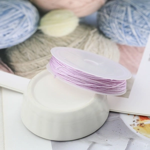 Macro detail of purple braided nylon cord for jewelry making on white spool