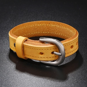 Macro detail of brown leather bracelet with vintage metal buckle and stitching on black surface