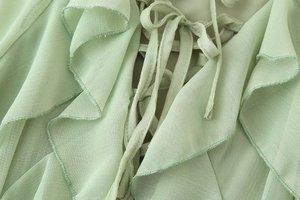 Detail eines hellgrünen Chiffonkleids mit Volants und Schnürung am Ausschnitt