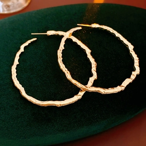 Gros plan de boucles d'oreilles créoles dorées avec texture martelée sur velours