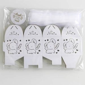 Flat lay of DIY white elephant gift boxes with silk ribbons and thank you tags in package