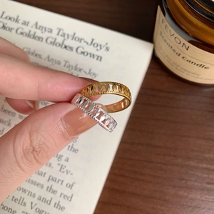Detail of gold and silver hollowed olive leaf rings held against a cozy background
