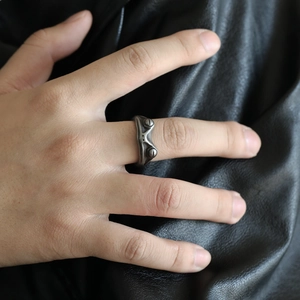Close-up of vintage silver frog ring on hand with dark leather background texture