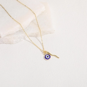 Detailed close-up of blue evil eye and gold chili pepper charms on a fine gold chain