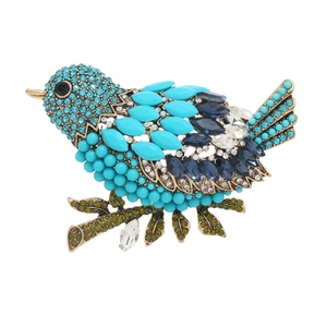 Vintage magpie brooch with turquoise beads and deep blue rhinestones on a gold branch