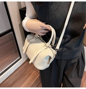 Detail view of cream pleated bucket bag with fine texture and pale gold metal hardware