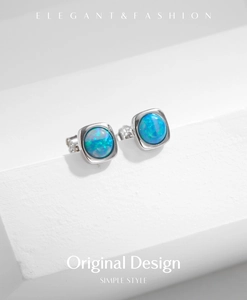 Macro detail of silver square stud earrings featuring vibrant blue opal inlay on a white stand