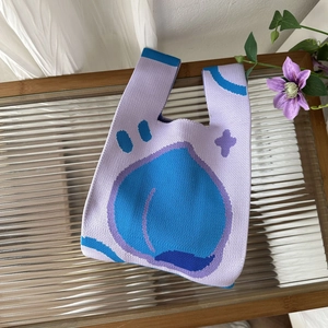Detail of light purple knitted tote bag with blue peach pattern on textured glass