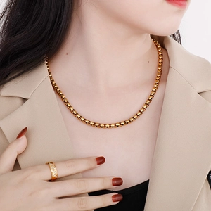 Close-up of a gold box chain necklace and matching ring set on a professional model