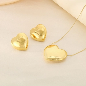 Vue détaillée d'une parure collier et boucles d'oreilles cœur doré sur tissu