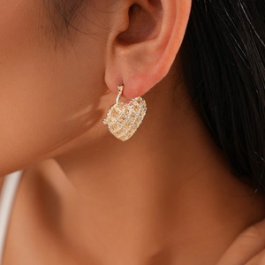 Close-up of heart-shaped hollow earrings in gold finish worn by a fashion model