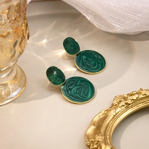Detailed macro view of dark green marble texture enamel earrings with gold trim