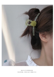 Detail of light green floral hair claw clip on model with elegant matte finish