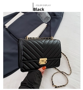 Close-up of black quilted chain bag with gold rectangular metal lock and woven strap
