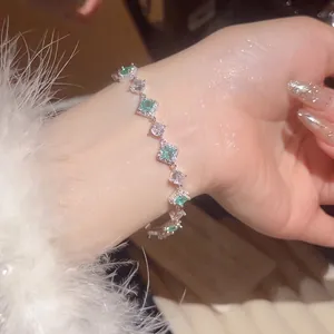 Elegant silver bracelet with green rhombic zircon stones on a model wrist for luxury look