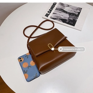Sac bandoulière vintage marron posé à côté d'un iPhone 11 pour comparaison