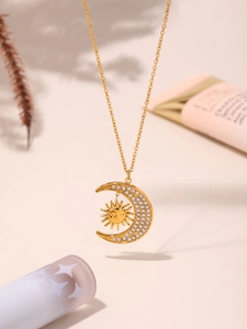 Detail of 18K gold necklace with celestial sun and moon pendant inlaid with zircons