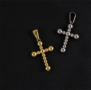 Detail of beaded cross pendants in gold and silver finishes on a black textured surface