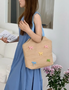 Detailed view of handmade woven straw tote bag decorated with colorful crochet bows