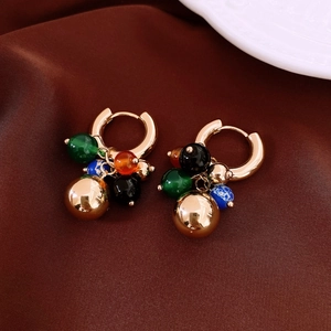 Détail de boucles d'oreilles bohèmes dorées avec perles colorées sur velours brun