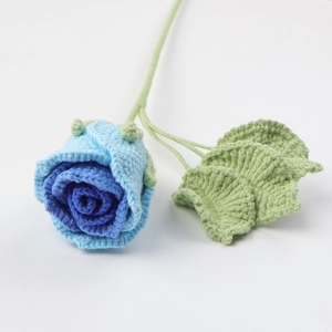 Detailed view of a handmade blue gradient crochet rose with green yarn leaves