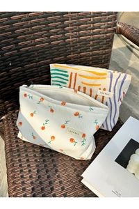 Close-up of corduroy toiletry bags with floral and geometric patterns on a woven chair