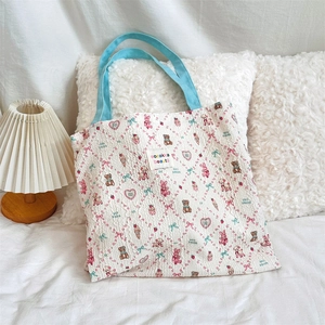 Detail view of canvas tote bag featuring cute animal prints and a woven label accent