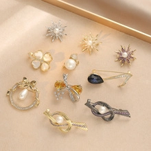 Flat lay of diverse floral and star brooches with pearls and crystals on beige background