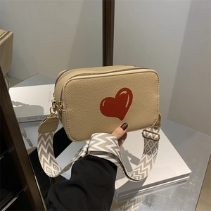 Beige crossbody bag with red heart pattern and geometric weave shoulder strap