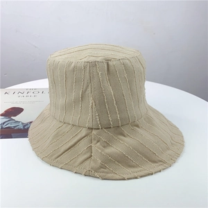 Détail des rayures effilochées sur un chapeau bob beige à large bord en toile coton
