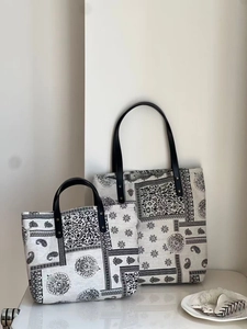 Detail of two paisley canvas tote bags with black leather handles and metal rivets