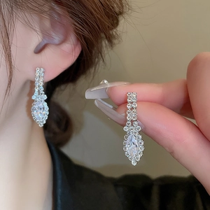 Detail view of teardrop pendant earrings with sparkling cubic zirconia on a female model