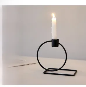 Detail of minimalist black metal geometric candle holder with a burning spiral candle