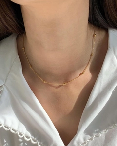 Detailansicht der mehrlagigen Goldperlenkette an einem Model im weißen Hemd