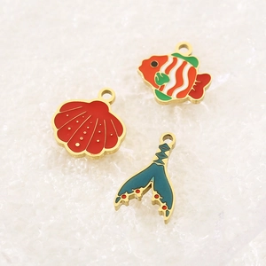 Detail of colorful enamel fish, shell, and mermaid tail charms with gold metal bases