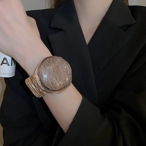 Detailed view of wide gold layered cuff bracelet with large glittering brown resin stone