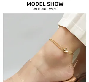 Detail of double-layer 18K gold bead anklet with a white butterfly pendant on ankle