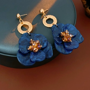 Macro detail of vintage floral earrings with blue marble petals and golden texture hoops