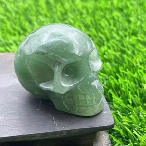 Detailed close-up of a 5cm hand-carved green gemstone skull on a dark wooden base