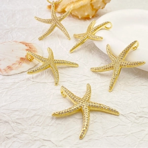 Starfish pendants in gold finish with sparkling zircons on a white textured background