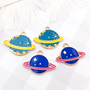 Detailed view of DIY alloy enamel planet charms for jewelry making on soft white feathers