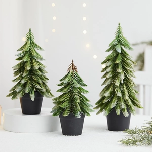 Miniature green Christmas trees with gold glitter in black pots for holiday table decor