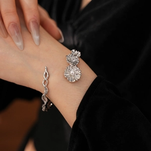 Close-up of vintage silver flower bangle with pearls worn by a model on black velvet