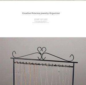 Detail of wall-mounted black metal jewelry rack featuring multiple hooks for necklaces