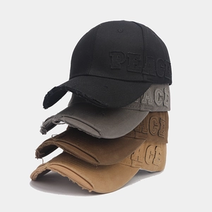 Detail of distressed baseball caps with PEACE embroidery in four neutral vintage colors