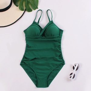 Flat lay of dark green ruched one-piece swimsuit with cross V-neck and summer accessories