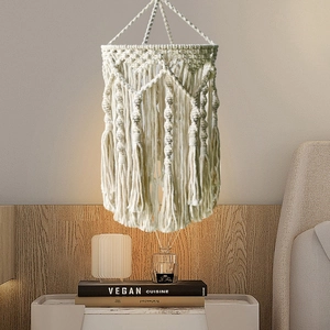 Bohemian macrame cotton lampshade with fringe tassels hanging in a bedroom setting