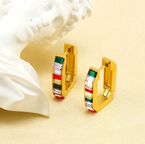 Macro detail of geometric 18K gold earrings with vibrant rectangular zircon stones