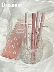 Close-up of four pink gradient dual-tip highlighters in a glass on white silk fabric