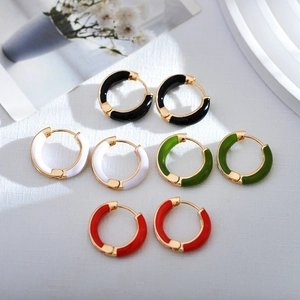 Detail view of geometric enamel hoop earrings in black, white, green, and red colors